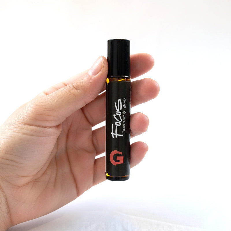 Hand holding the GOGHINI Focus Oil roll-on pen, label facing camera