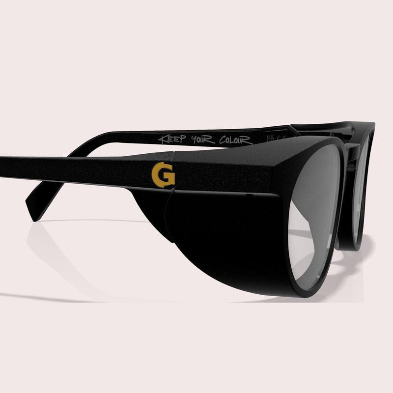 GOGHINI Focus Frames™ shown in side profile view, displaying the full peripheral blocking shield design on black frames with yellow 'G' logo and 'Keep Your Colour' text visible on the temple arm
