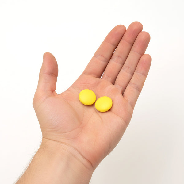 Two yellow silicone disc ear grips held in an open palm