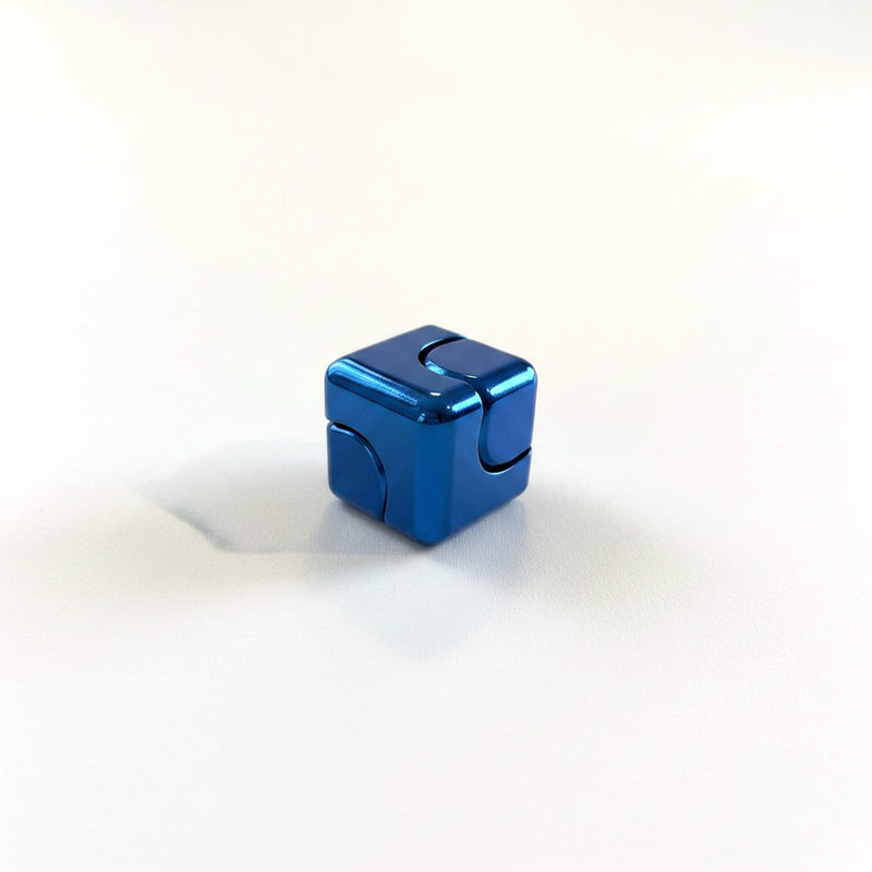 Blue anodised metal fidget cube resting on a corner edge, curved seam visible